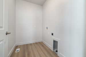 Clothes washing area featuring hookup for an electric dryer, light hardwood / wood-style floors, and hookup for a washing machine