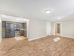 Unfurnished living room featuring built in shelves and light hardwood / wood-style flooring