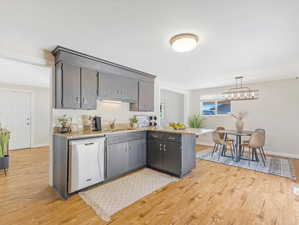 Kitchen featuring hanging light fixtures, kitchen peninsula, dishwasher, light hardwood / wood-style flooring, and sink