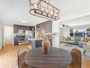 Dining space featuring ceiling fan with notable chandelier and light hardwood / wood-style floors