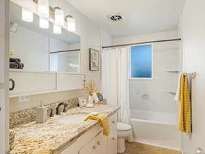 Full bathroom featuring vanity, shower / bath combo with shower curtain, and toilet