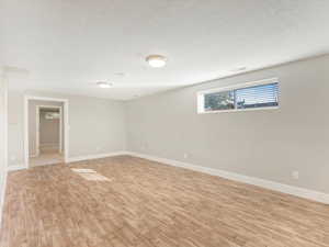 Spare room with light wood-type flooring and a textured ceiling