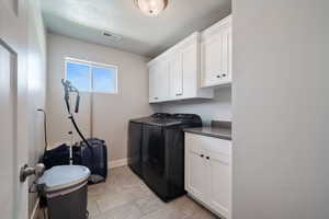 Laundry area featuring independent washer and dryer, cabinets, and a textured ceiling