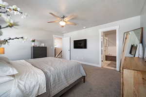 Bedroom featuring ceiling fan, carpet, a textured ceiling, and ensuite bath