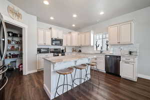 Kitchen featuring light stone counters, a textured ceiling, appliances with stainless steel finishes, dark hardwood / wood-style floors, and a center island