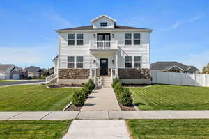 Front of property with a balcony and a front lawn