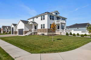 View of front property with a balcony, a garage, a porch, and a front lawn