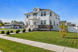 View of front facade featuring a front lawn, a balcony, and a garage