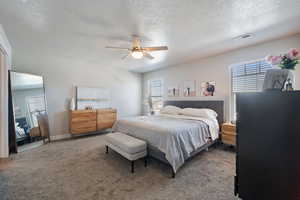 Bedroom with ceiling fan, carpet floors, and a textured ceiling