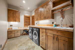 Laundry area featuring washer and clothes dryer, sink, and cabinets