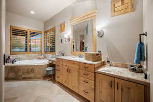 Bathroom featuring tiled bath, tile patterned floors, and vanity