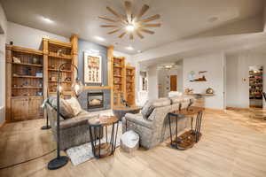 Living room featuring ceiling fan, light hardwood / wood-style flooring, and a tiled fireplace