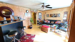 Living room featuring bamboo flooring, crown molding, and ceiling fan