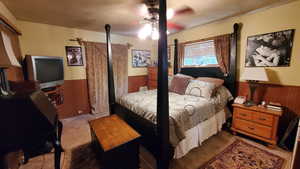 Carpeted bedroom featuring wood walls and ceiling fan