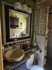 Bathroom featuring a tile shower, tile walls, and vanity