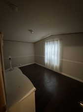 Unfurnished room featuring lofted ceiling and dark hardwood / wood-style flooring