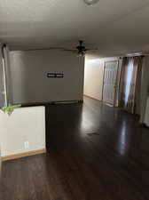 Unfurnished room with ceiling fan, dark wood-type flooring, and a textured ceiling