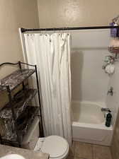 Bathroom with shower / bath combination with curtain, toilet, and tile patterned floors