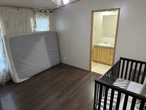 Bedroom featuring sink, a crib, crown molding, dark hardwood / wood-style floors, and ensuite bath