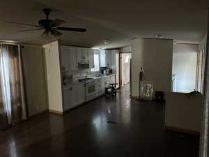 Kitchen featuring ceiling fan, white cabinets, dark wood-type flooring, white range with gas stovetop, and a textured ceiling