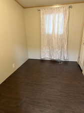 Spare room featuring dark hardwood / wood-style floors, ornamental molding, and a textured ceiling