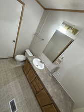 Bathroom featuring a textured ceiling, vaulted ceiling, vanity, and toilet