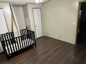 Bedroom with a textured ceiling, dark hardwood / wood-style floors, and ornamental molding