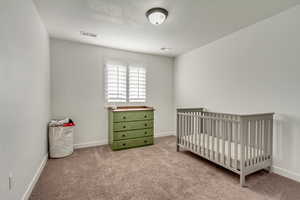 Bedroom with a nursery area and light colored carpet