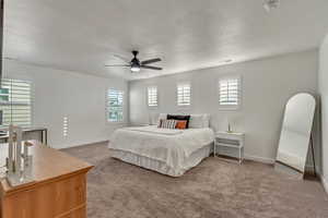 Bedroom featuring carpet flooring, a textured ceiling, and ceiling fan