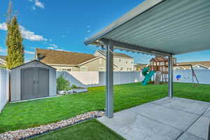 View of yard with a playground, a patio, and a storage unit