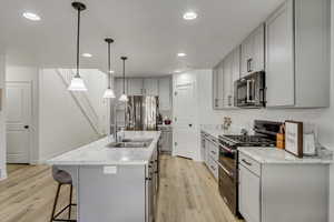 Kitchen with decorative light fixtures, appliances with stainless steel finishes, light wood-type flooring, and sink