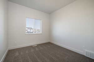 Unfurnished room featuring dark carpet