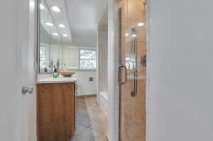 Bathroom with tile patterned flooring, vanity, and a shower with door