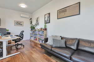 Office space with an AC wall unit and wood-type flooring