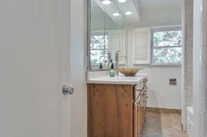 Bathroom with tile patterned flooring, vanity, and a washtub