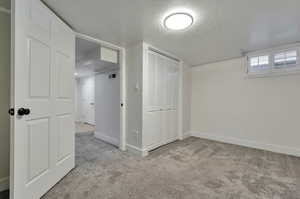 Unfurnished bedroom with a textured ceiling and light colored carpet