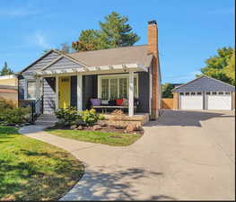 View of front of home featuring a front yard, a garage, an outdoor structure, and a porch