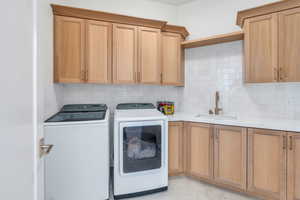 Laundry room by kitchen with sink and custom cabinetry