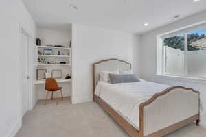 Carpeted bedroom featuring built in desk