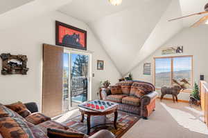 Living room featuring carpet floors, vaulted ceiling, and ceiling fan