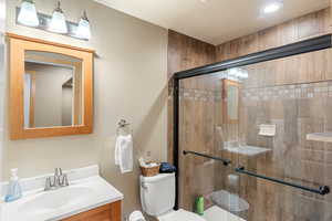 Bathroom featuring walk in shower, vanity, and toilet