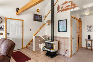 Tiled entrance foyer featuring tile walls, beamed ceiling, and a wood stove