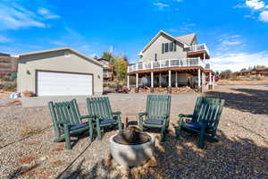 Back of property featuring a deck, a fire pit, and a garage