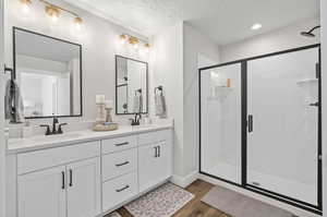 Bathroom with wood-type flooring, vanity, a textured ceiling, and a shower with door