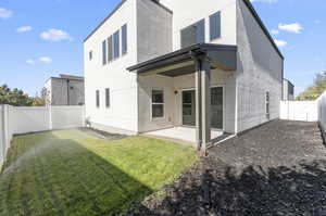 Rear view of property with a patio and a lawn