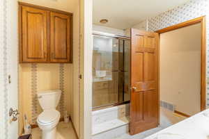 Bathroom featuring toilet, tile patterned floors, and an enclosed shower