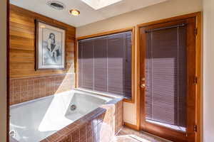 Bathroom with a skylight, tiled bath, and tile patterned floors