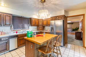 Kitchen featuring stainless steel refrigerator with ice dispenser, butcher block counters, light tile patterned flooring, and a kitchen island