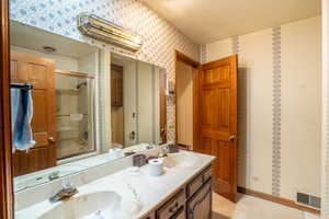 Full bathroom with a textured ceiling, combined bath / shower with glass door, vanity, and toilet