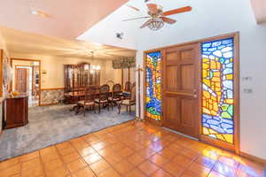 Carpeted entrance foyer featuring ceiling fan with notable chandelier